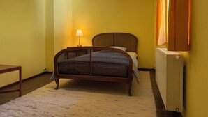 A room with a bed, a nightstand, a lamp, a radiator, and a window with curtains. - Nusshof Vacation Home for up to 9 people (Berchtesgaden)