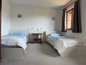 A room with two single beds, a small wooden table, and a window with curtains. - Nusshof Vacation Home for up to 9 people (Berchtesgaden)