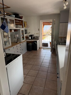 A compact kitchen with white cabinets, a stove, and a sink. There is a small window providing natural light. - Nusshof Vacation Home for up to 9 people (Berchtesgaden)