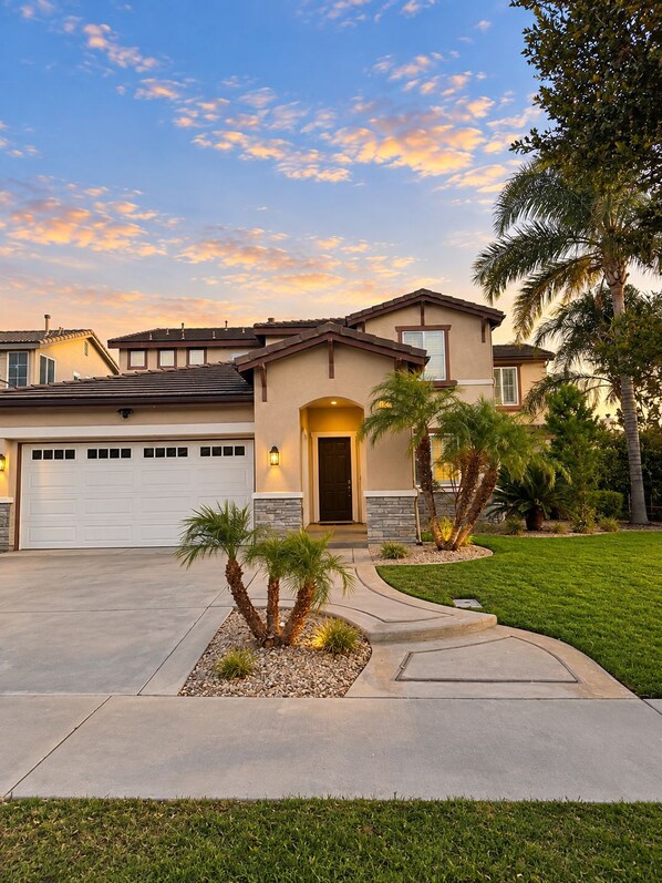 A two-story house with a garage, a driveway, and a well-maintained lawn.