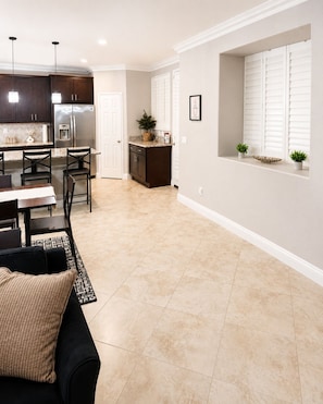A modern kitchen with dark cabinets, a stainless steel refrigerator, and pendant lighting. - Luxury SoCal Escape w/ Resort-Style Pool (Fontana)