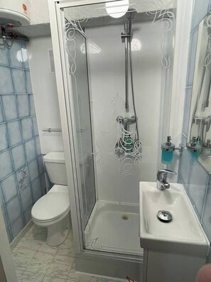 Un bagno con doccia vetrata, un water e un lavandino.