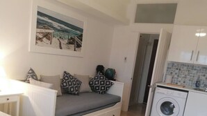 Ein gemütlicher Raum mit Bett, Sofa, Waschmaschine und Küchenzeile.