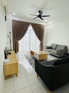 A modern living room with a sofa, a coffee table, a TV stand, and a ceiling fan. - Oak & Ivory Home • Cozy Clean 3BR • 5km to Airport (Kota Samarahan)