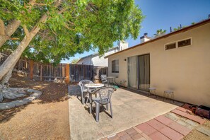 A patio with a table and chairs, a tree, and a building with a sliding door. - Moreno Valley Family Retreat Near Dtwn Riverside (Moreno Valley)