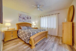 A bedroom with a wooden bed, a nightstand, a lamp, a ceiling fan, a mirror, and a wooden wardrobe. - Moreno Valley Family Retreat Near Dtwn Riverside (Moreno Valley)