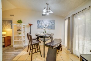 A dining area with a round table, chairs, a bench, a chandelier, a painting, and a plant. - Moreno Valley Family Retreat Near Dtwn Riverside (Moreno Valley)