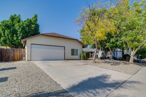 A single-story house with a garage, a gravel driveway, and a wooden fence. - Moreno Valley Family Retreat Near Dtwn Riverside (Moreno Valley)