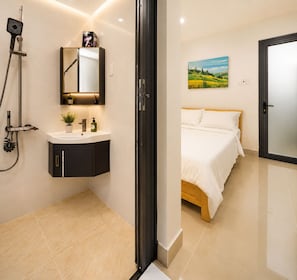A modern bathroom with a shower, sink, and mirror. - Homestay Na (Ho Chi Minh)