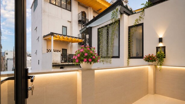 Un bâtiment moderne doté d’un balcon, d’une plante en pot et d’un luminaire.