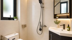 Une salle de bain moderne équipée d’un WC, d’une douche, d’un lavabo et d’un miroir.