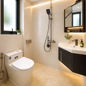 Et moderne badeværelse med toilet, bruser, vask og spejl.