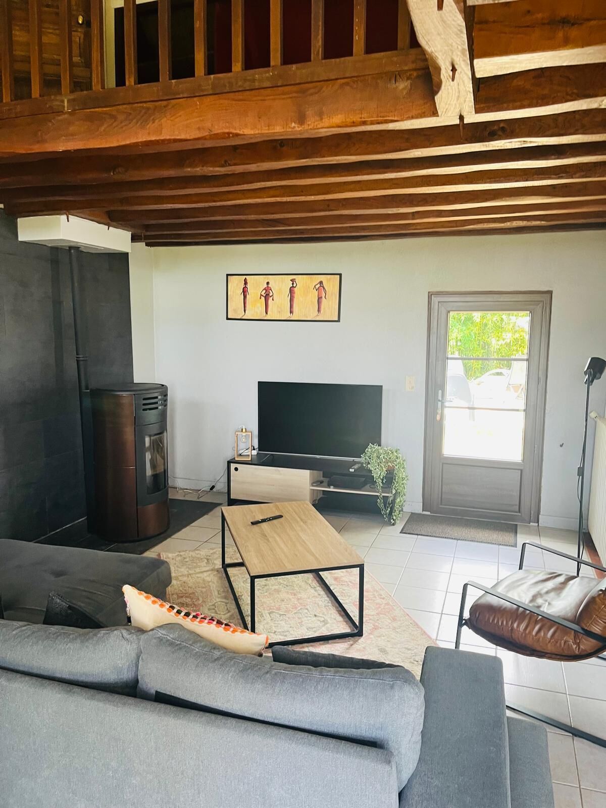 A living room with a sofa, a coffee table, a TV, a fireplace, and a door leading outside.