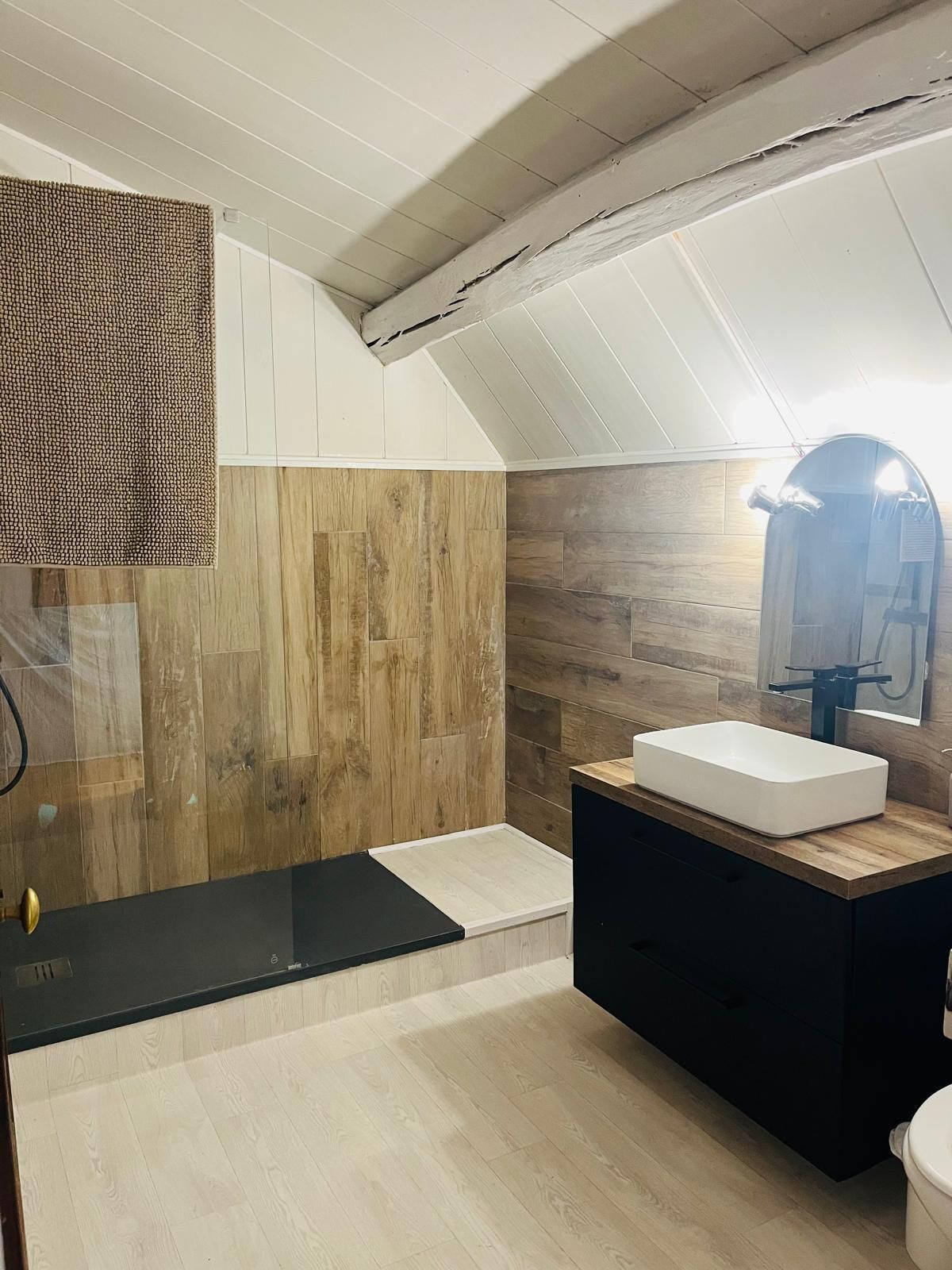 Een moderne badkamer met een houten wastafelmeubel, een grote spiegel en een inloopdouche.
