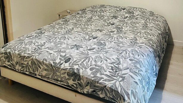 Ein Schlafzimmer mit Bett, Klimaanlage, Fenster mit schwarzem Rahmen und Pendelleuchte.