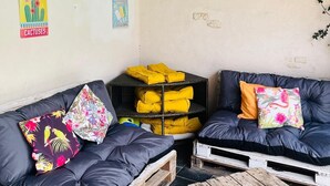 Ein rustikaler Außenbereich mit Holzpaletten, einer schwarzen Couch und einem Holztisch.