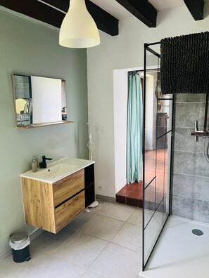 A modern bathroom with a wooden vanity, a mirror, a shower with a glass door, and a hanging light fixture. - A charming country house half an hour from Beauval. (Argy)