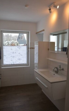 A bathroom with a window, a sink, and a mirror. - Vrbo Property (Altenau)
