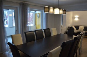 A dining area with a long table and chairs, a sofa, and a hanging light fixture. - Vrbo Property (Altenau)