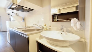 A modern bathroom with a double sink, a large mirror, and a built-in heater. - New Normal Hotel in ASAHIBASHIEKI (Naha City)
