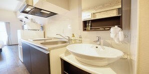 A modern bathroom with a double sink, a large mirror, and a built-in heater. - New Normal Hotel in ASAHIBASHIEKI (Naha City)