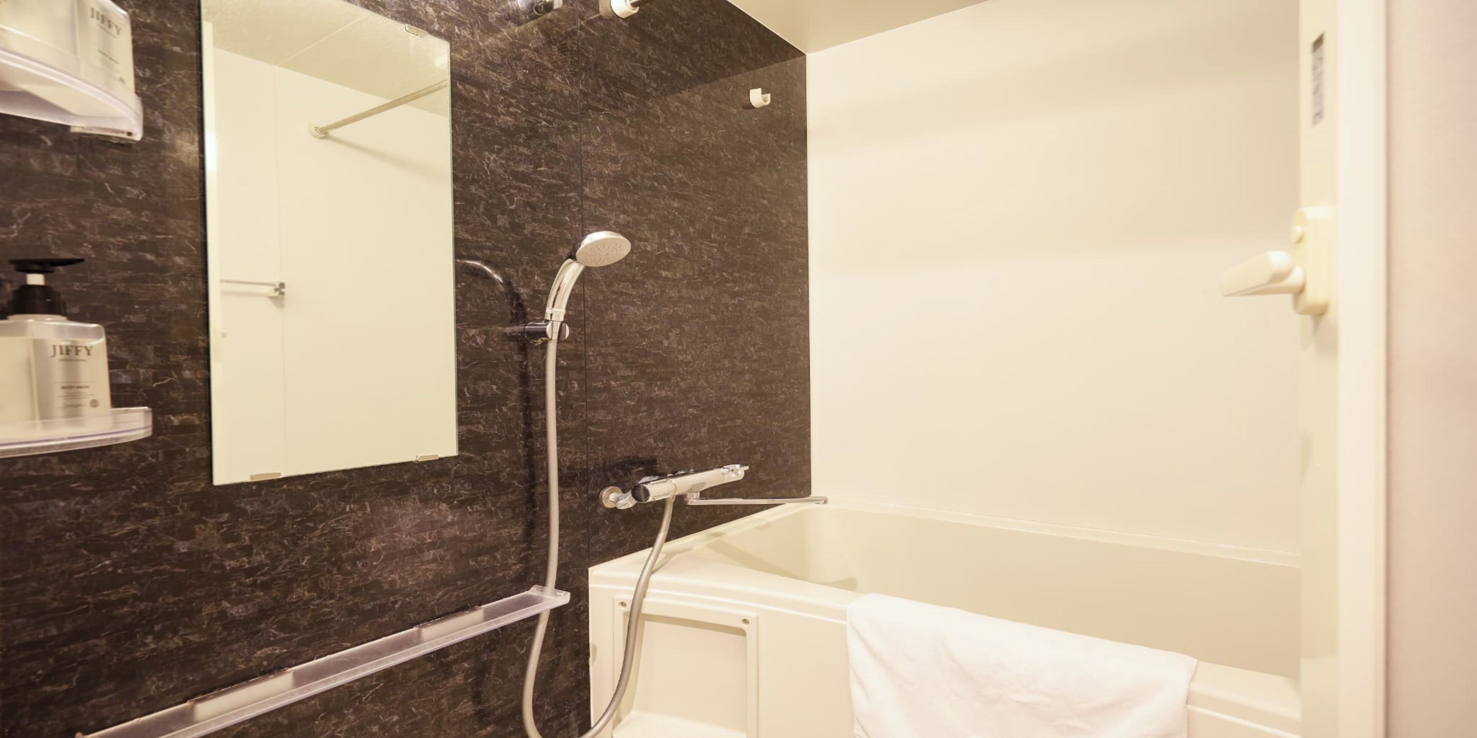 Baño con bañera, ducha, espejo y toallero.
