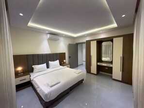 A modern hotel room with a large bed, a vanity with a mirror, and a wardrobe. - 103 JRE comfortable and accessible retreat (Amman)