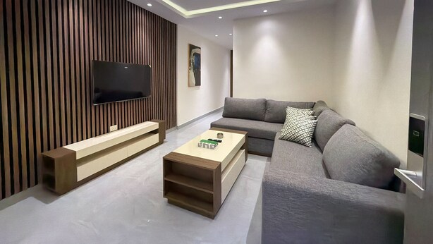 Un soggiorno moderno con televisione a schermo piatto, un divano grigio, un tavolino in legno e un condizionatore d'aria a parete.