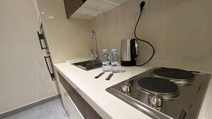 Un angolo cottura con un fornello in acciaio inossidabile, un lavandino e due bottiglie d'acqua.