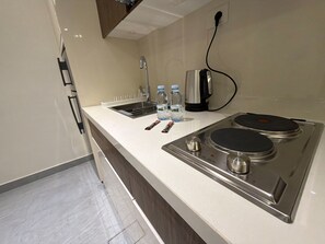 A kitchenette with a stainless steel stove, a sink, and two water bottles. - 103 JRE comfortable and accessible retreat (Amman)