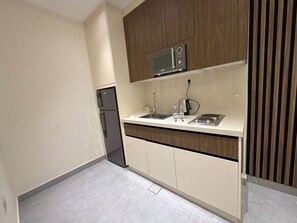 A modern kitchen with a built-in microwave, a sink, and a stove. - 103 JRE comfortable and accessible retreat (Amman)