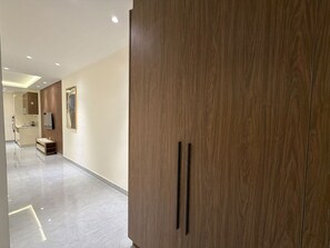 A modern hotel corridor with a wooden wardrobe, a small kitchenette, and a mirror. - 103 JRE comfortable and accessible retreat (Amman)