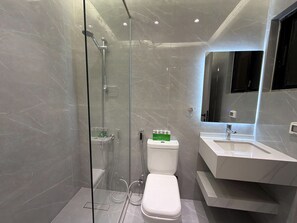 A modern bathroom with a glass-enclosed shower, a white toilet, and a sink with a mirror above it. - 201 JRE apartment with stunning boulevar (Amman)