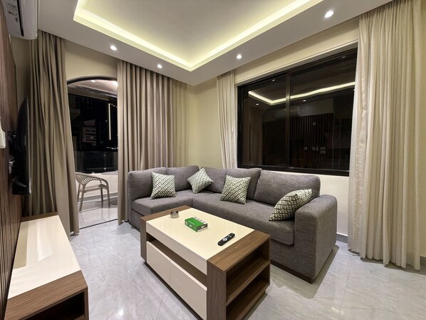 A modern living room with a sofa, a coffee table, and a TV. - 201 JRE apartment with stunning boulevar (Amman)