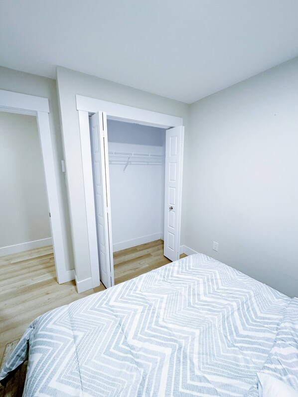 Un dormitorio con cama, armario y suelo de madera.