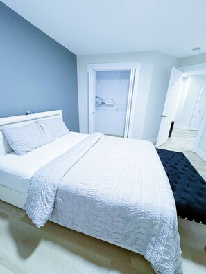 A bedroom with a bed, a wardrobe, and a door leading to another room. - Luxury 3-Bedroom Full House Near Magnetic Hill (Moncton)