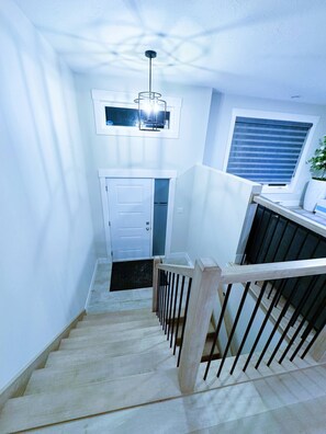 Eine Treppe mit einem Holzgeländer, einer weißen Tür und einem Fenster mit Jalousien.
