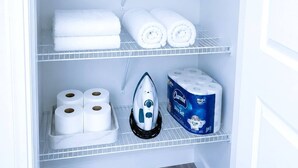 A storage closet with shelves holding rolled towels, a bottle of hand soap, a jar of cotton balls, and a box of Charmin toilet paper. - Modern 3-Bedroom Retreat Near Moncton Hospital and Downtown (Moncton)