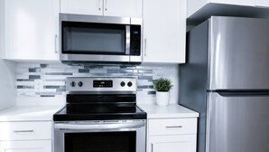 A modern kitchen with white cabinets, a stainless steel microwave, oven, and refrigerator. - Modern 3-Bedroom Retreat Near Moncton Hospital and Downtown (Moncton)