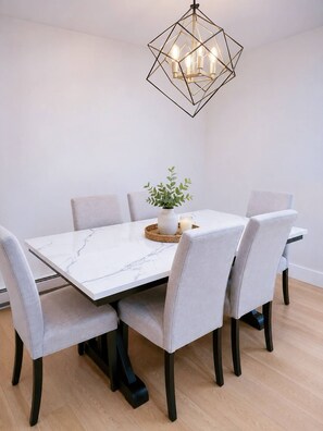 A dining table with six chairs, a geometric chandelier, and a small plant centerpiece. - Stylish 3-Bedroom Full House Near Magnetic Hill (Moncton)