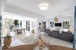 Ein modernes Wohnzimmer mit einer Couch, einem Essbereich und einem großen Fenster.
