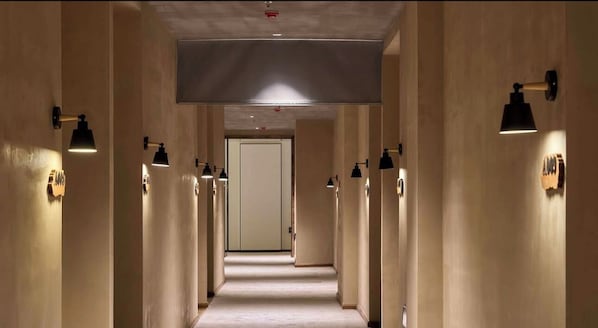 A hotel corridor with multiple doors, wall-mounted lights, and a ceiling light. - Qingbai Valley Hotel (Shenzhen)