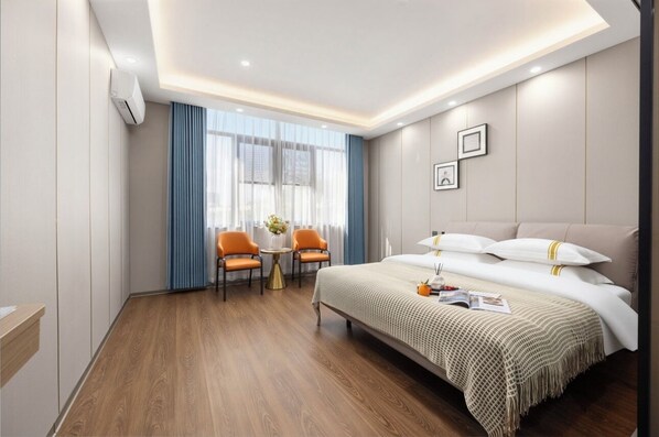 Una habitación de hotel con una cama, dos sillas, una mesita con un florero y una ventana con cortinas.