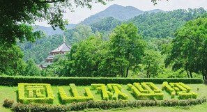 A traditional Japanese temple surrounded by lush greenery and a well-maintained garden with geometric hedge patterns. - Qingbai Valley Hotel (Shenzhen)