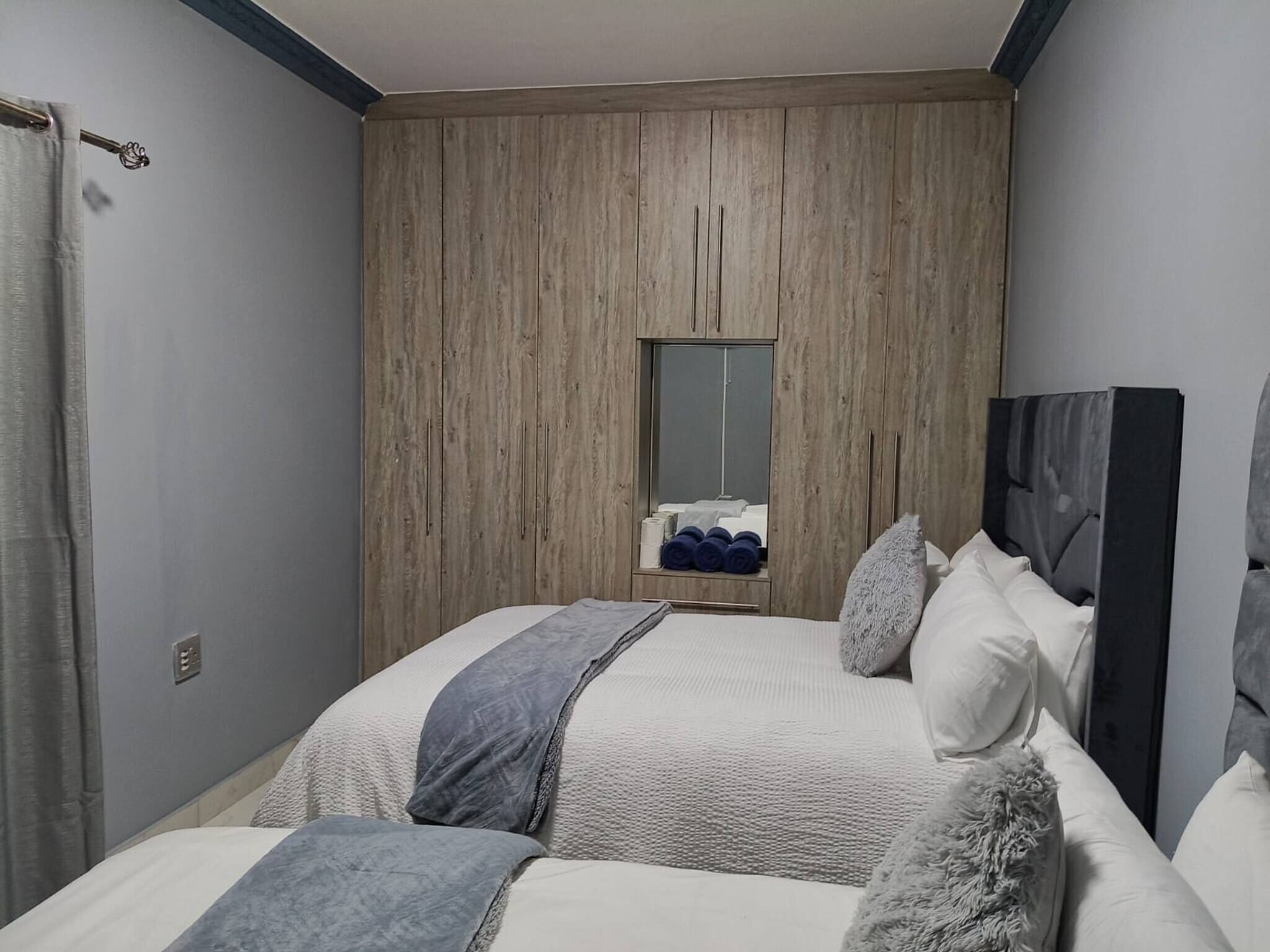 Ein Schlafzimmer mit einem großen Bett, einem Kleiderschrank, einem Spiegel und einem Fenster.