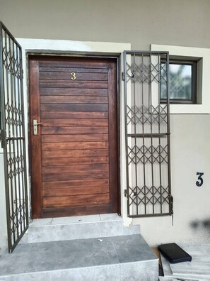 Una porta de fusta amb una reixa metàl·lica, el número '3' a la porta, i una petita finestra sobre la reixa.
