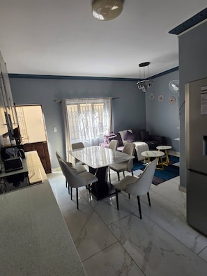 Un espai modern d'estar amb zona de menjador, sofà i cuina.