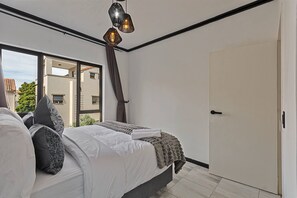A bedroom with a bed, a window, and a door. - Zalari Luxe Loft A, Spacious 2-Bed Loft, Paulshof (Sandton)