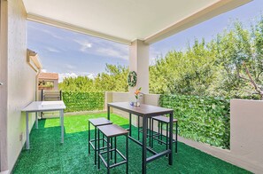 An outdoor patio with a table and chairs, a small table with a vase, and a view of a garden. - Zalari Loft B, Nature-Inspired 2 Bed Loft Paulshof (Sandton)