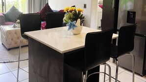 A modern kitchen with a central island, black chairs, a refrigerator, and a dining table. - Zalari Loft B, Nature-Inspired 2 Bed Loft Paulshof (Sandton)
